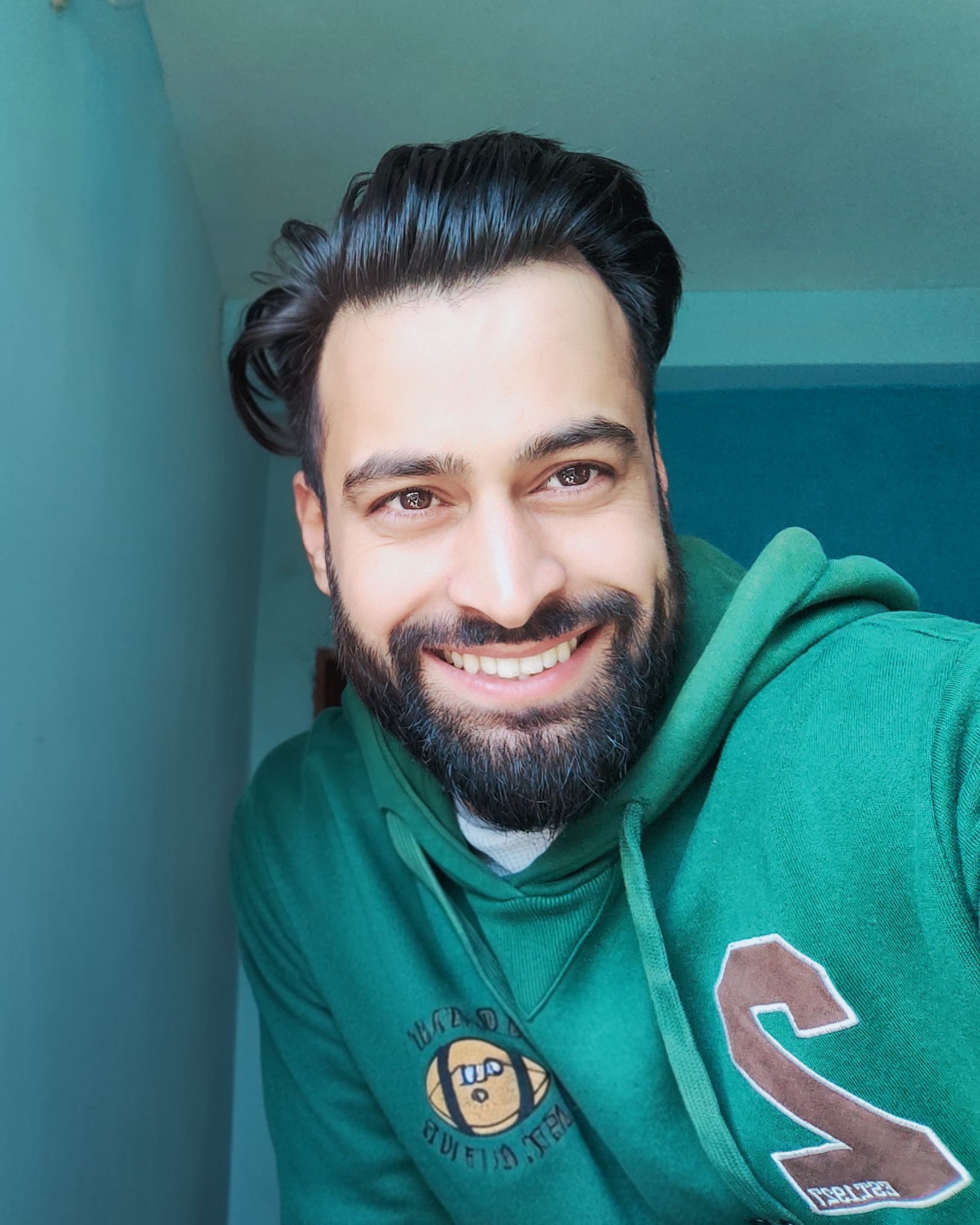 Inayat Abbas Malla smiling in a green hoodie